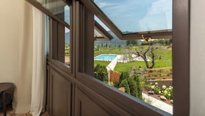 A room with a view of a backyard including a swimming pool, garden, and trees. - Suite..... (Iseo)