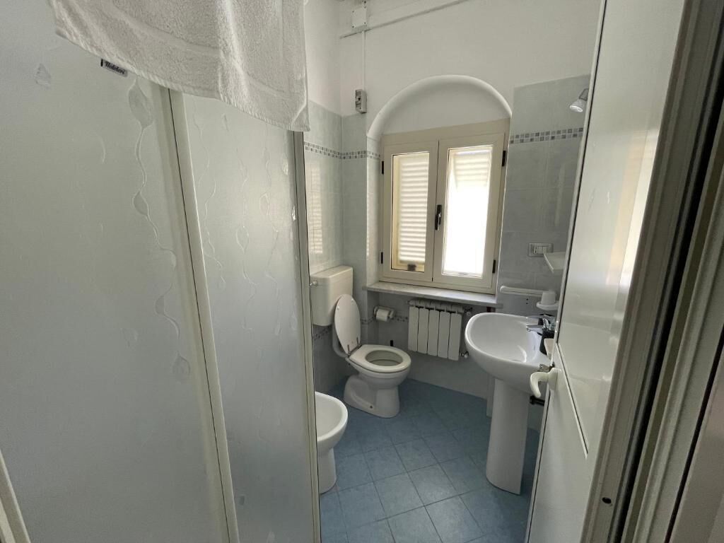 A bathroom with a toilet, sink, and shower area.