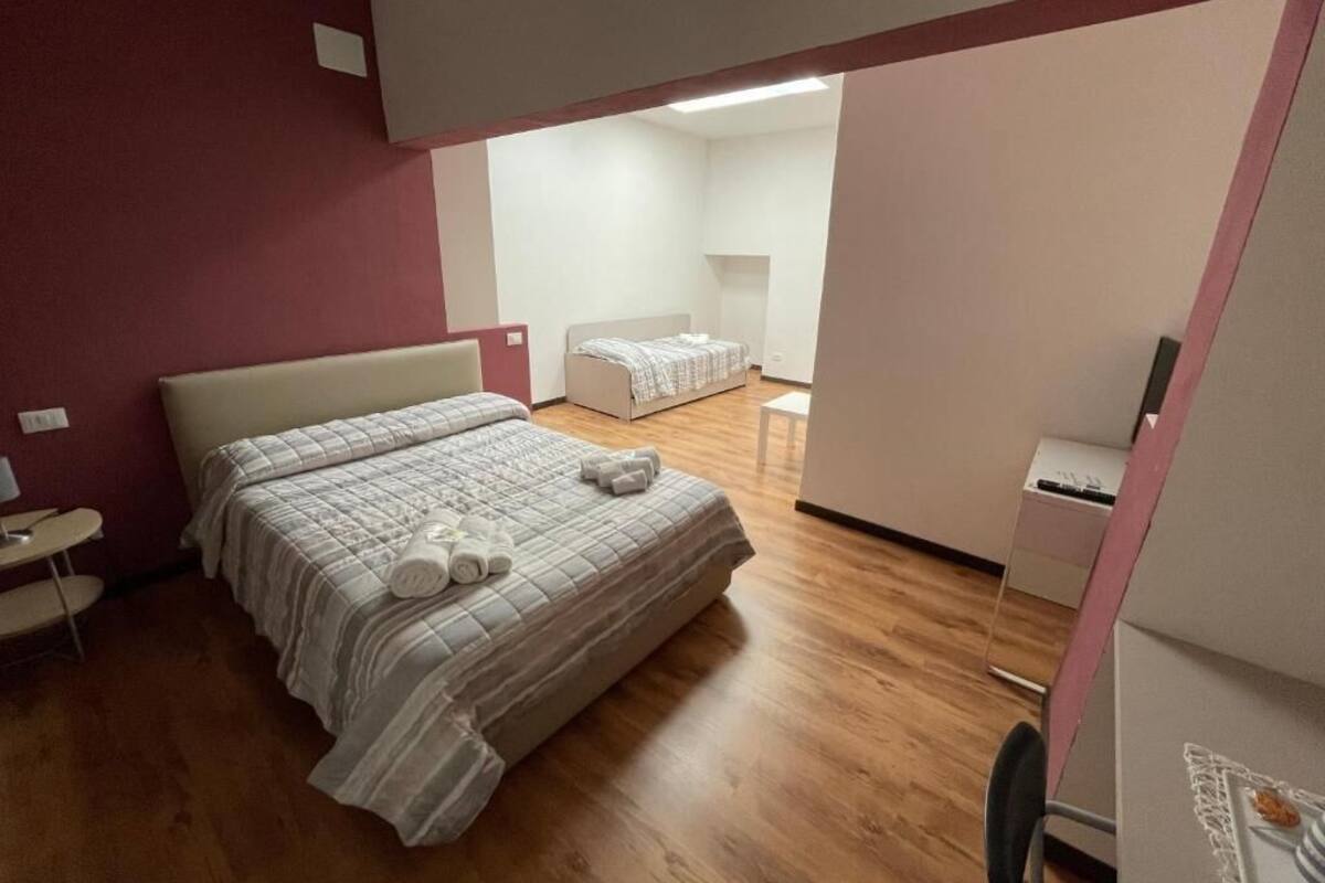 A modern hotel room with a large bed, a small desk, and a chair.