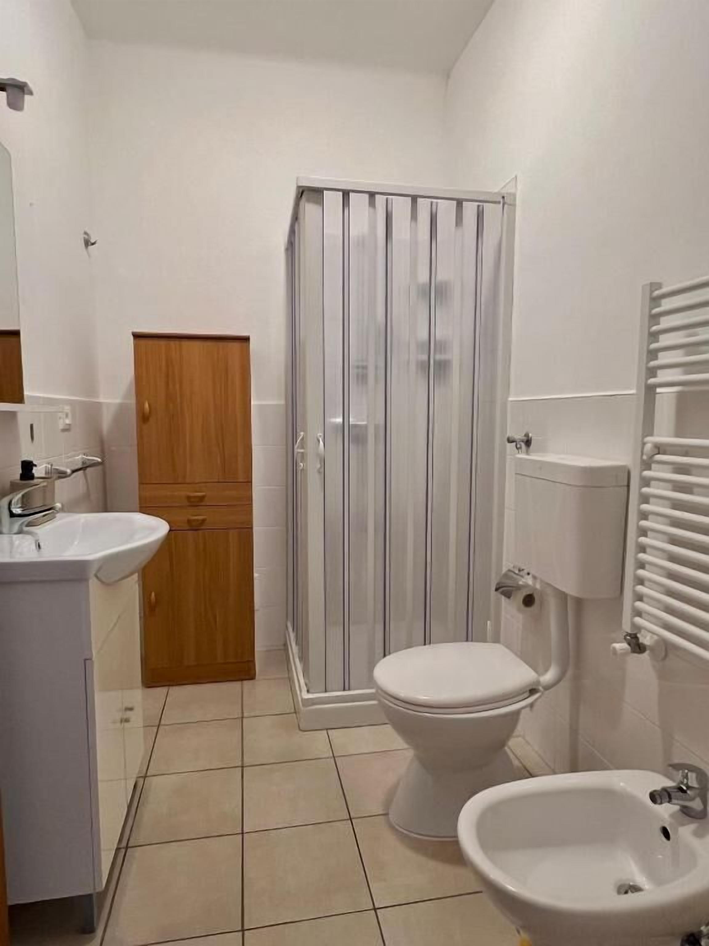 A bathroom with a toilet, bidet, sink, and shower enclosure.