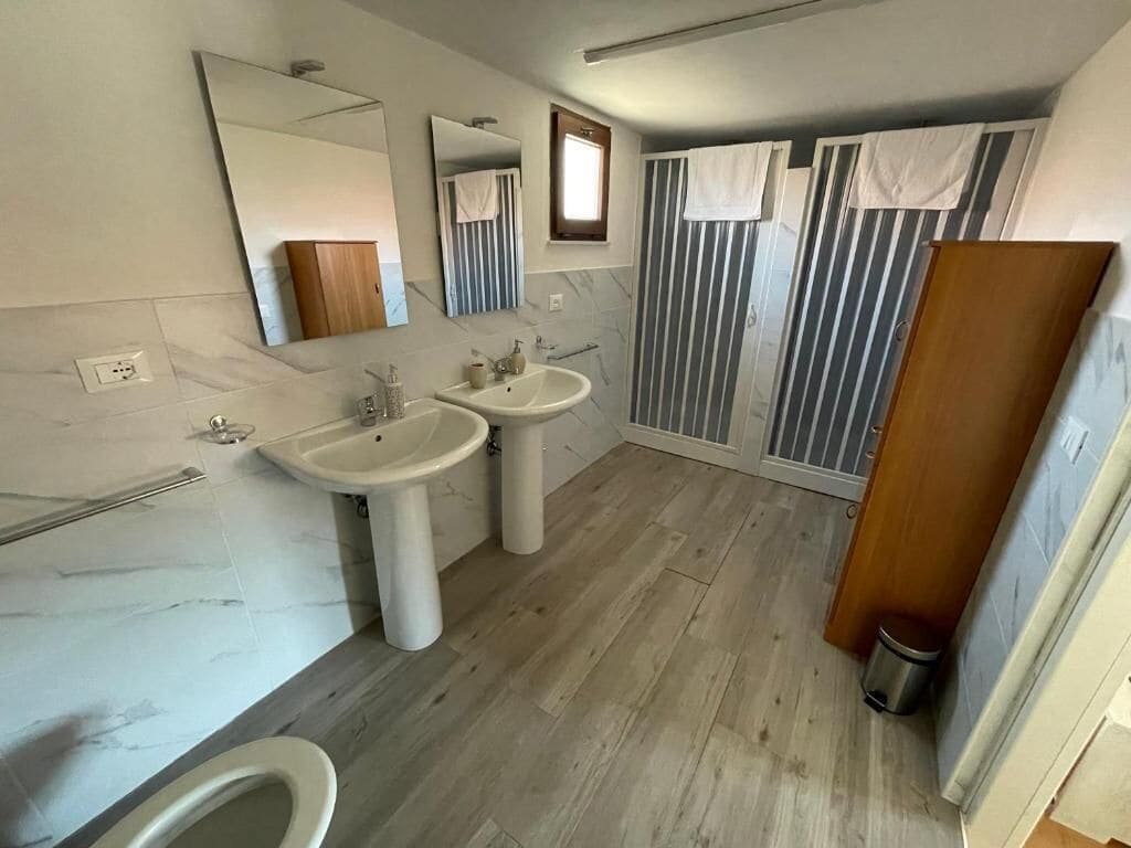 A modern bathroom with two sinks, a toilet, and a shower area.