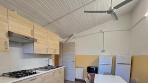 A modern kitchen with wooden cabinets, a gas stove, and a ceiling fan.