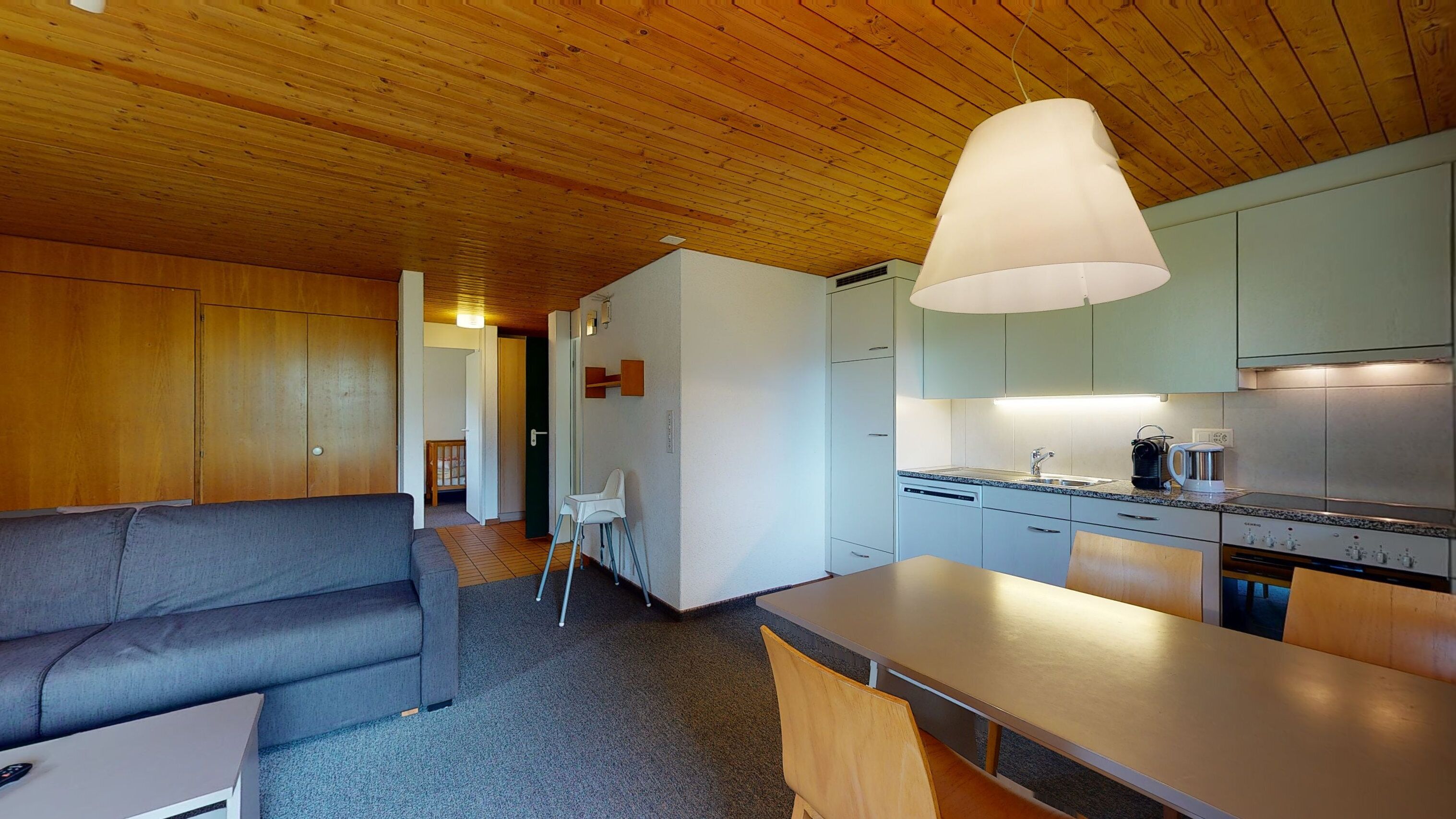 A compact living space with a sofa, dining table, and kitchenette.