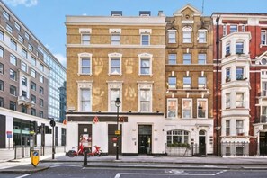 A multi-story building with a ground-floor entrance, a bicycle parked outside, and a street view. - 2VH Virginia House, 31 Bloomsbury Way by City Living London (London)