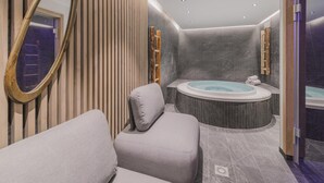 Ein modernes Badezimmer mit einer großen Badewanne, einem Spiegel und einer Sitzecke.