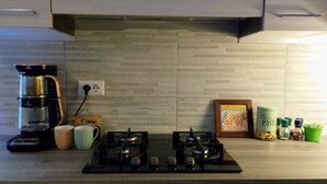 Een keuken met een gasfornuis, een koffiezetapparaat, potten en een kookboek voor pasta.