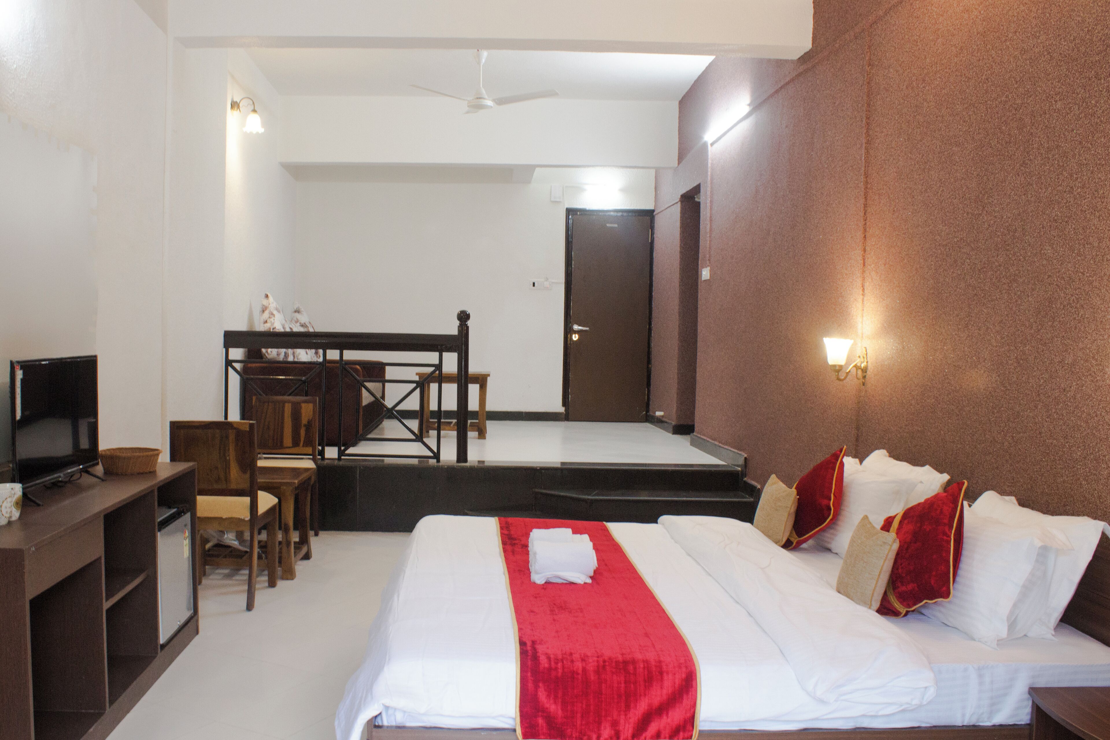 A hotel room with a bed, a desk, a television, and a staircase leading to another room.
