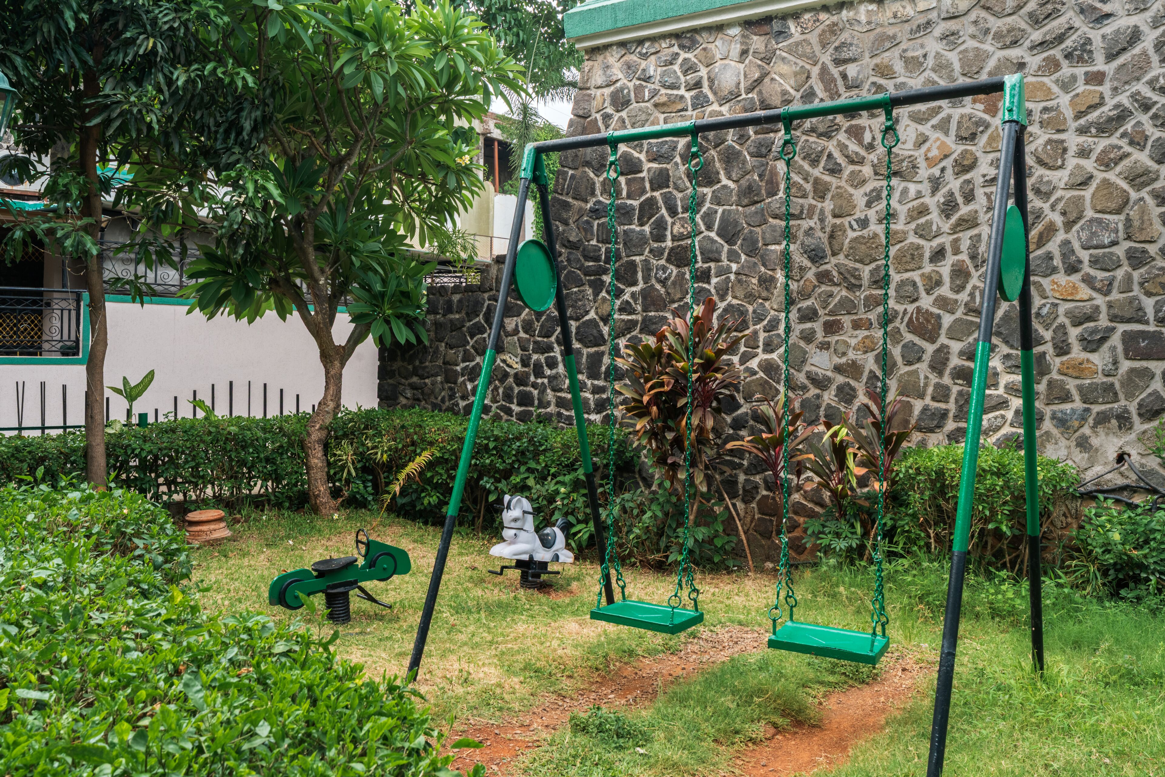 A stone wall, a swing set, and a garden path.