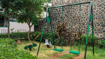 A stone wall, a swing set, and a garden path.