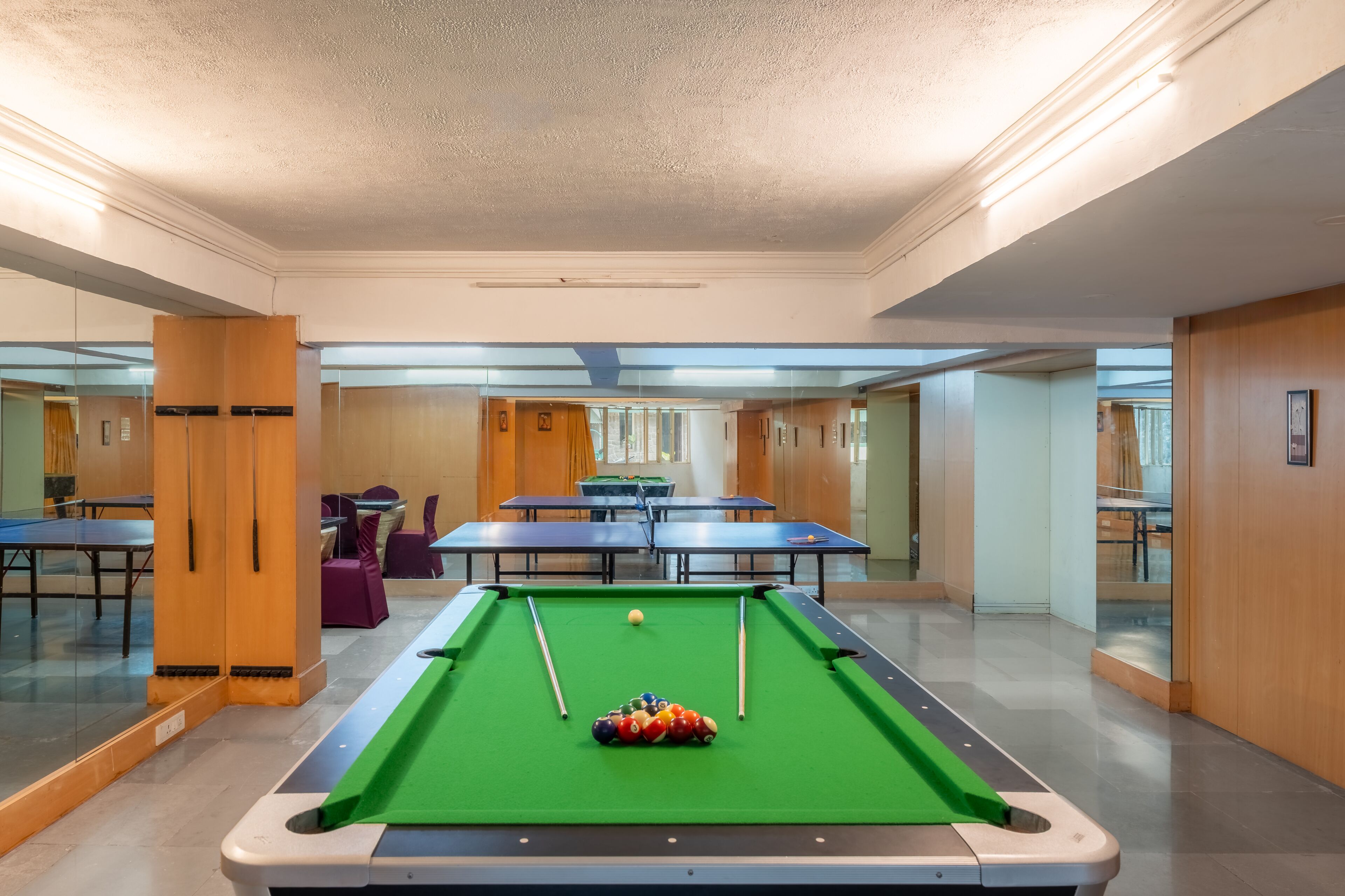 Une table de billard avec des billes, une table de ping-pong et une table de snooker dans un espace intérieur bien éclairé.