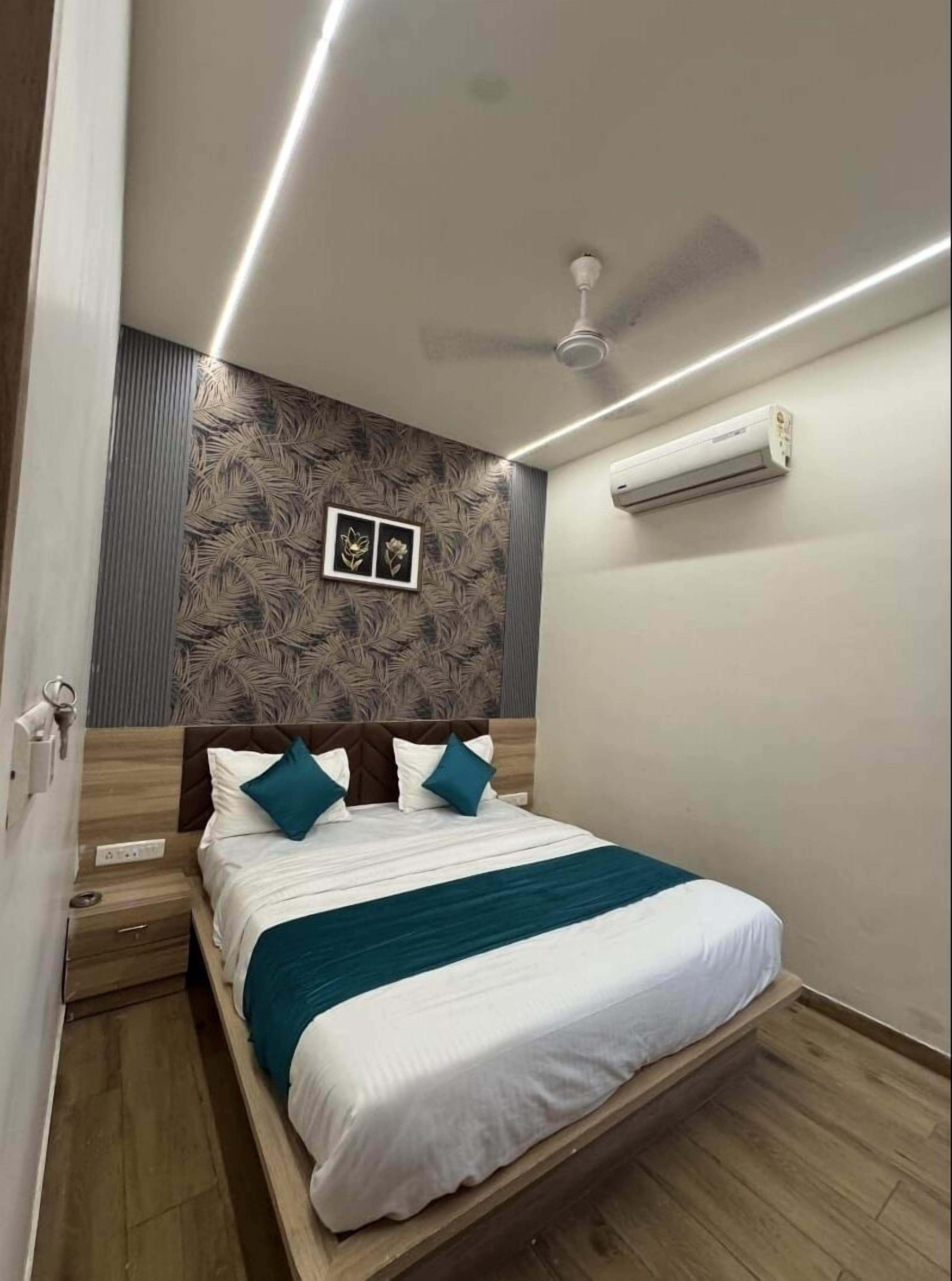 Quarto moderno com cama, ventilador de teto, ar condicionado e uma obra de arte na parede.