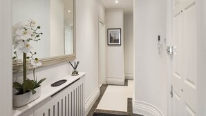 A hallway with a white radiator, a mirror, and a framed picture on the wall. - Kensington Apartment | Hyde Park, Portobello, Royal Albert Hall (London)