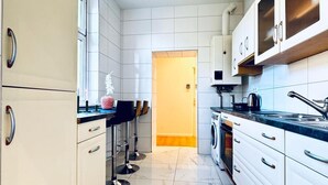 Een moderne keuken met witte kastjes, een marmeren vloer en een ingebouwde wasmachine.