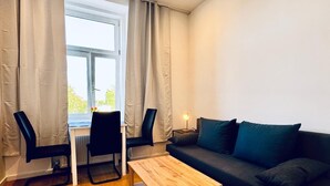 Een moderne woonkamer met een houten salontafel, een donkere bank en twee zwarte stoelen.