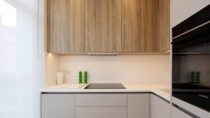 Eine moderne Küche mit Holzausstattung, einem schwarzen Herd und einer weißen Arbeitsplatte.