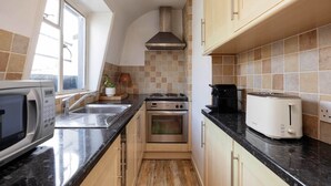 Een kleine keuken met een magnetron, fornuis, oven en broodrooster.