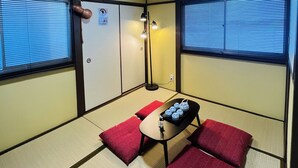 A traditional Japanese room with tatami flooring, a low table with a tray of water bottles, and a red cushion. - THE KAGAYA KYOTO hachijokuchi (Kyoto)