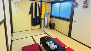 Um quarto japonês tradicional com piso de tatame, uma mesa baixa com um tabuleiro de saquê e uma janela com persianas.