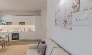 A modern kitchen with white cabinets, a built-in oven, and a dining area with a white table and chairs. - The Paraguays by Varenna Holidays (Bellano)