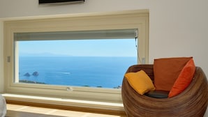 Una habitación con un gran ventanal que ofrece vista al mar y a la costa distante.