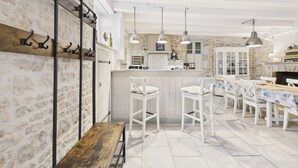 A spacious kitchen with white cabinetry, a wooden bench, and a dining area with white chairs. - Charming house for 8 people, 800m from the beach (Le Bois-Plage-en-Ré)