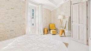A bedroom with a bed, a yellow armchair, a floor lamp, and a wardrobe. - Charming house for 8 people, 800m from the beach (Le Bois-Plage-en-Ré)