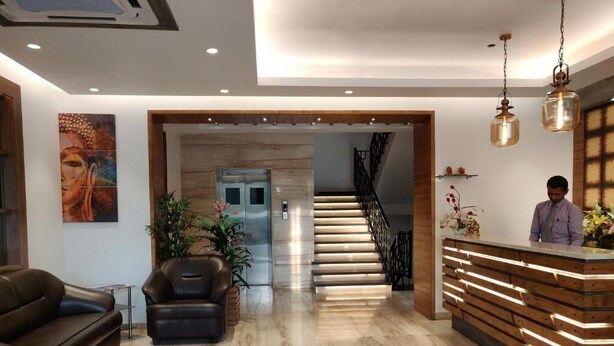 A modern lobby with a reception desk, a staircase, and a seating area. - Hotel yelchiko (Varanasi)