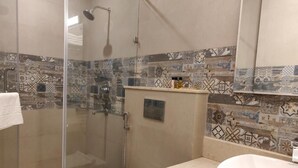A bathroom with a glass-enclosed shower, a toilet, and a sink with a mirror. - Hotel yelchiko (Varanasi)