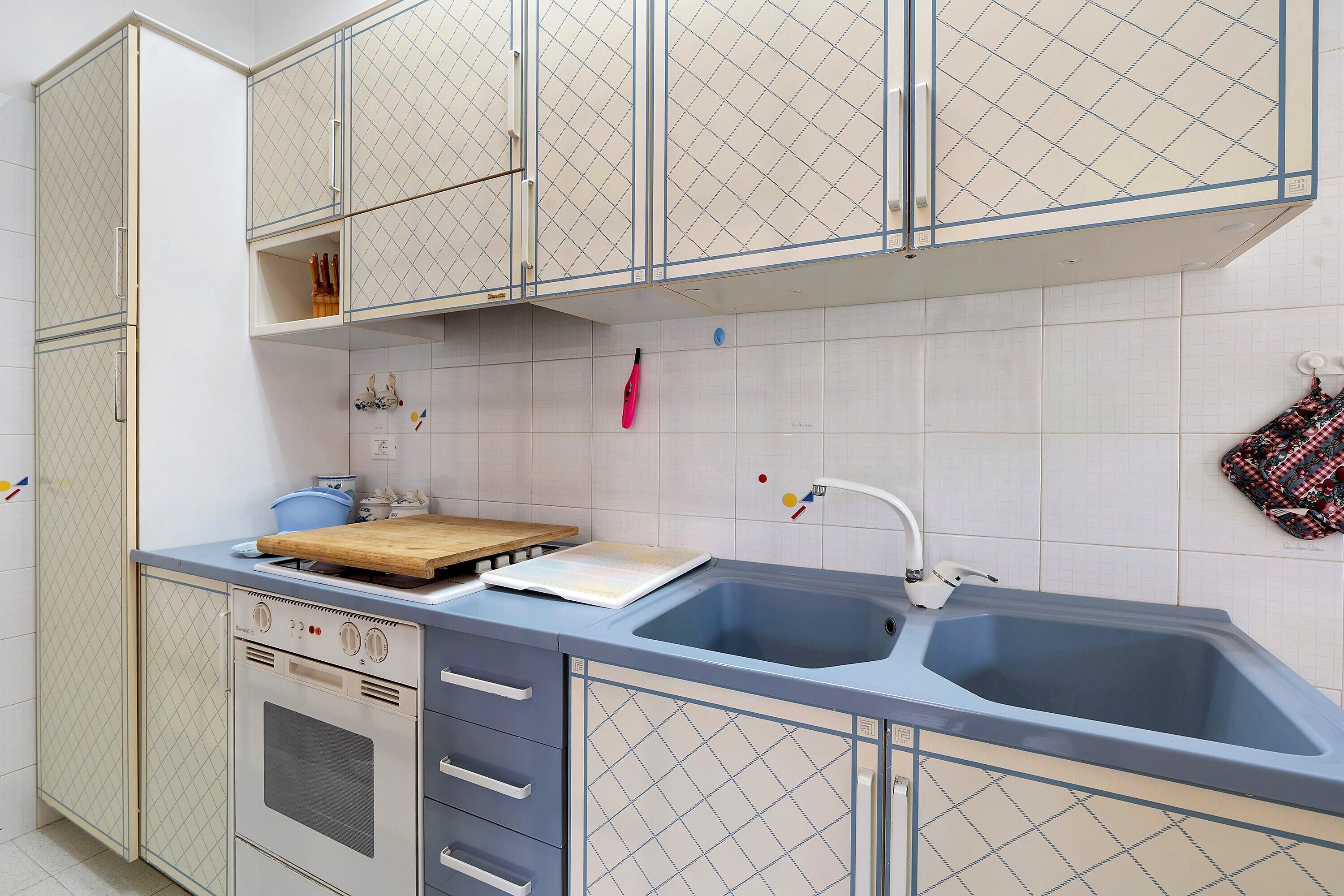 A kitchen with a double sink, a stove, and a wooden cutting board.