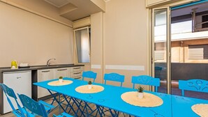 Eine kompakte Küche mit Spüle, kleinem Kühlschrank und einem Essbereich mit blauem Tisch und Stühlen.