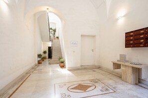 A hallway with a marble floor, a wooden bench, and a staircase leading to another room. - Apartment Near the Bari Train Station • A Comfortable & Convenient Stay in the City   (Bari)