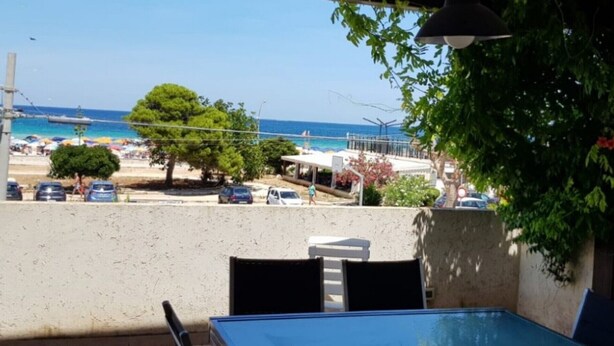 A balcony with a view of the beach, a table, chairs, and a hanging light fixture. - Villa 'Tra Cielo E Sabbia 2' with Sea View, Private Terrace and Air Conditioning (San Vito Lo Capo)