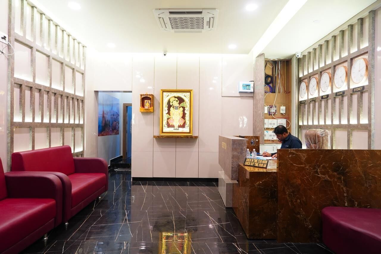 A hotel reception area with red seating, a marble reception desk, and clocks displaying various city names.