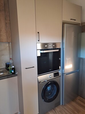 Eine kompakte Küche mit Einbauofen, Waschmaschine und Kühlschrank.