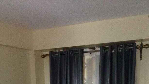 A hotel room with a bed, a patterned floor, and dark curtains. - Koyaro Centre (Nairobi)