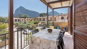 A balcony with a table, chairs, and a view of a mountain. - Holiday Home 'A Casa Di Titti' with Mountain View, Wi-Fi, and Air Conditioning (San Vito Lo Capo)