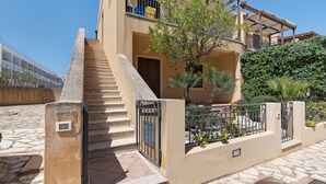 A multi-story building with a staircase leading to an upper floor, a balcony with a railing, and a small tree in the courtyard. - Holiday Home 'A Casa Di Titti' with Mountain View, Wi-Fi, and Air Conditioning (San Vito Lo Capo)