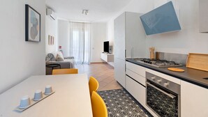 A modern kitchen with a gas stove, oven, and a dining area with a table and chairs. - Holiday Home 'A Casa Di Titti' with Mountain View, Wi-Fi, and Air Conditioning (San Vito Lo Capo)