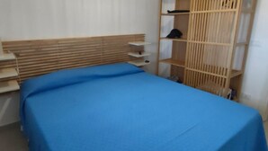 A room with a bed, a wooden headboard, a shelf unit, and a window with blinds. - Casa Sole di Sicilia: Sea View, Wi-Fi & Air Conditioning in San Vito Lo Capo (San Vito Lo Capo)