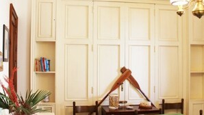 A room with a dining table, chairs, a bookshelf, and a large white wardrobe. - Villetta Sole: Holiday Home with Mountain View, Shared Terrace & Air Conditioning (San Vito Lo Capo)
