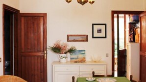 A dining area with a wooden door, a white table with a green tablecloth, and a painting on the wall. - Villetta Sole: Holiday Home with Mountain View, Shared Terrace & Air Conditioning (San Vito Lo Capo)
