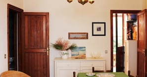 Uma sala de jantar com uma porta de madeira, uma mesa branca com toalha verde e um quadro na parede.