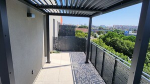 A covered outdoor area with a metal railing, a drainage grate, and a view of a cityscape in the background. - Appartement Résidence Terra Cotta  (Toulouse)
