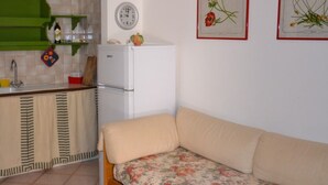 A kitchen with a refrigerator, a sink, and a green shelf with kitchen items.