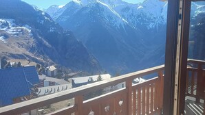 Une vue sur la montagne depuis un balcon doté d’une rambarde en bois.