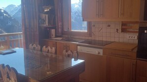 Une cuisine avec des meubles de rangement en bois, un four encastré et une fenêtre donnant sur les montagnes.