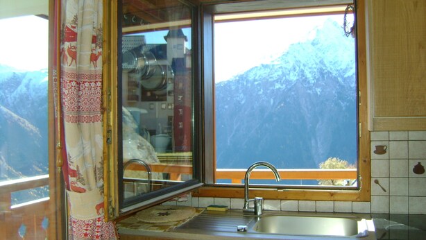 Une cuisine avec une fenêtre donnant sur un paysage montagneux.
