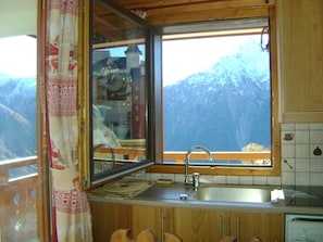 A kitchen with a window overlooking a mountainous landscape. - LES 2 ALPES, comfortable one-bedroom apartment with a private covered parking space at the foot of the slopes (Les Deux Alpes)