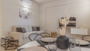 Ett modernt vardagsrum med en matplats, med en soffa, stolar, ett matbord med tallrikar och glas, och en tv som är monterad på väggen.