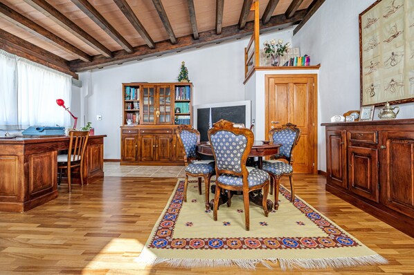Un coin repas en bois avec une table et des chaises, une bibliothèque et un téléviseur.